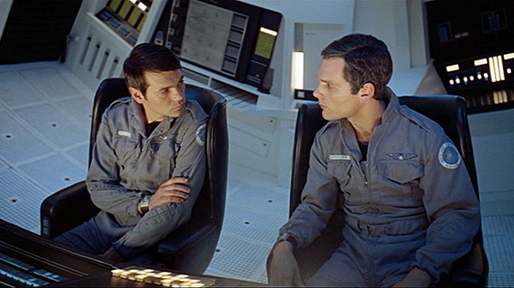 Astronauts Frank and Dave confer while seated in the centrifuge of the Discovery spaceship.